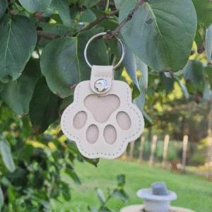 le porte-clé patte en simili cuir Un petit bijou unique, pensé pour garder un souvenir précieux de votre compagnon. Grâce à son espace transparent fermé par un bouton-pression, vous pouvez y glisser quelques poils de votre chien et l’emporter partout avec vous Un accessoire symbolique, durable et rempli d’émotion